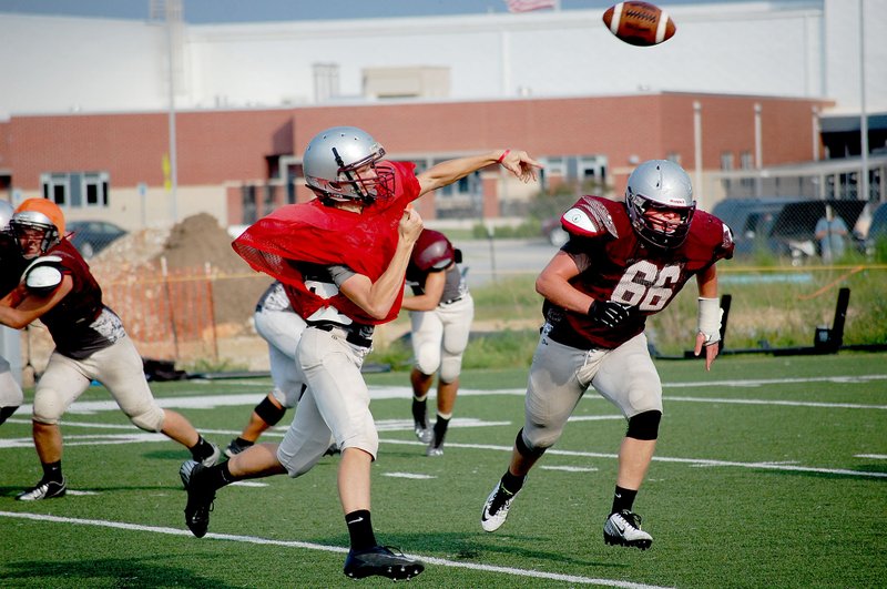 Graham Thomas/Siloam Sunday Siloam Springs junior quarterback Jordan Norberg avoids the defense while attempting a pass during practice Friday at Siloam Springs High School.