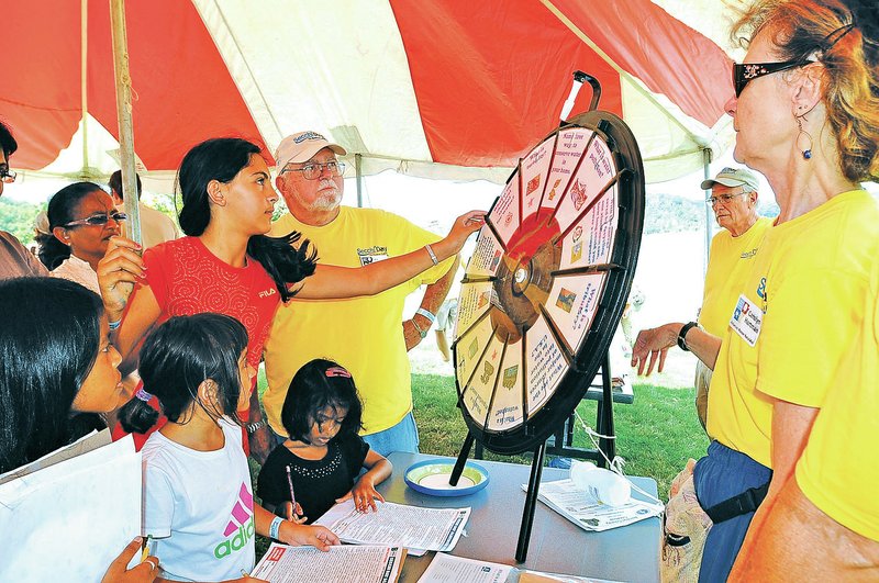 STAFF PHOTO FLIP PUTTHOFF Janna Morse, 10, spins the question wheel Saturday during a trivia game at Secchi Day at Prairie Creek park. Janna&#8217;s family, from West Fork, and friends used Secchi Day as an educational opportunity.