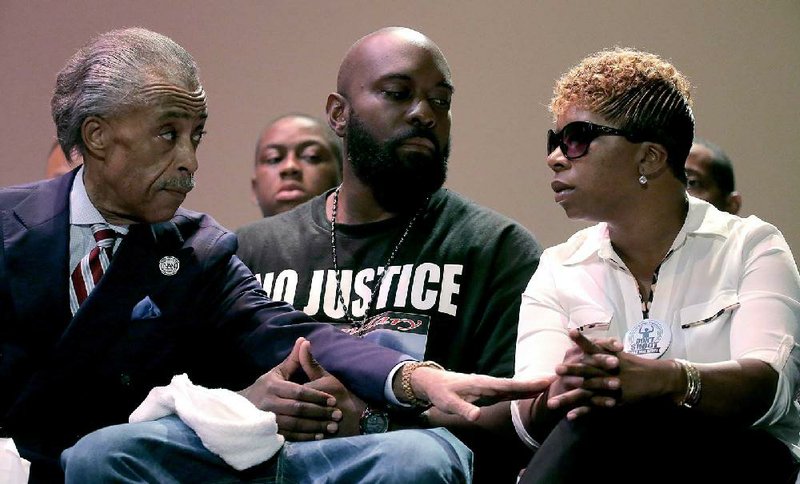 Rev. Al Sharpton speaks with parents of Michael Brown, Michael Brown Sr. and Lesley McSpadden during a rally at Greater Grace Church, Sunday, Aug. 17, 2014, for their son who was killed by police last Saturday in Ferguson, Mo. Brown's shooting in the middle of a street, following a suspected robbery of a box of cigars from a nearby market, has sparked a week of protests, riots and looting in the St. Louis suburb. (AP Photo/Charlie Riedel)