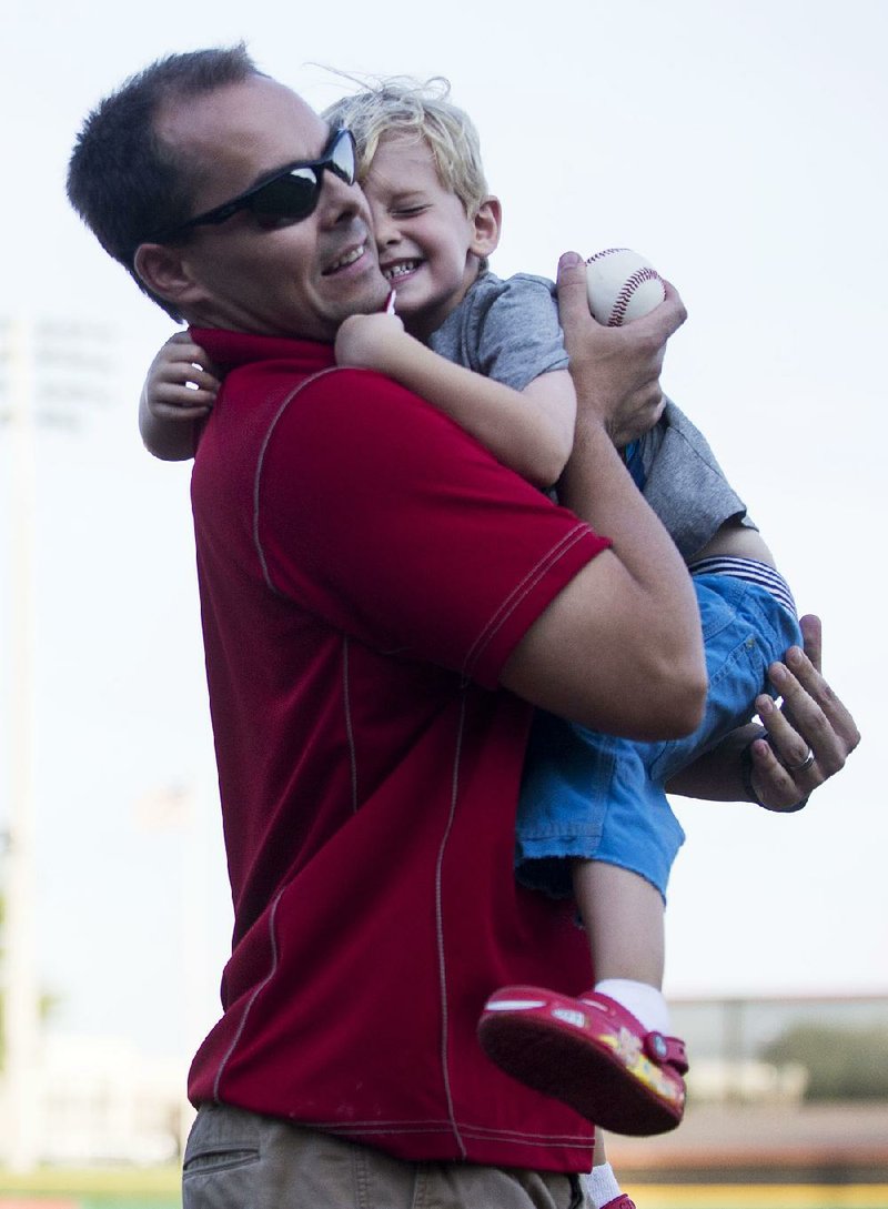 Arkansas Democrat-Gazette/Melissa Sue Gerrits - 07/25/2014 - David Palmer of with Entergy, receives a hug from son Hudson Palmer after throwing a ceremonial first pitch before a Travelers game July 25, 2014. 