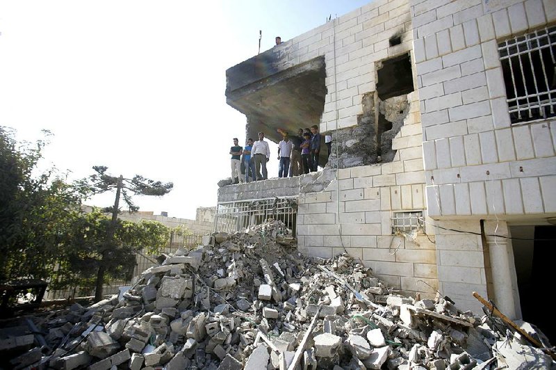 Palestinians stand in what is left of the home of Amer Abu Aisheh, one of three Palestinians identified by Israel as suspects in the killing of three Israeli teenagers, after it was demolished by the Israeli army in the West Bank city of Hebron, Monday, Aug. 18 , 2014. (AP Photo/Nasser Shiyoukhi)
