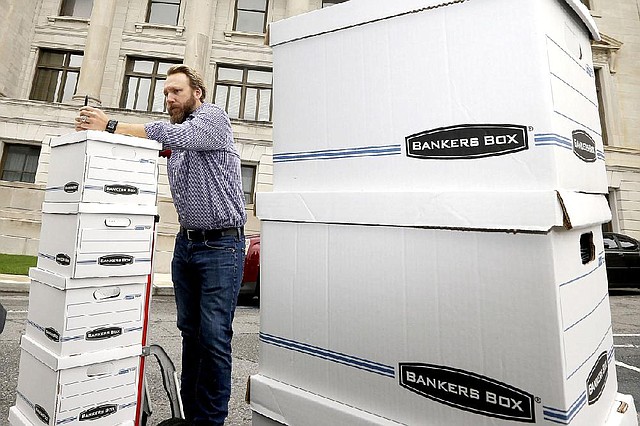 Greg Hale leans on boxes of petitions signed by supporters of a state minimum wage increase at the Arkansas state Capitol in Little Rock, Ark., before submitting them to be counted Monday, Aug. 18, 2014. Monday was the deadline for supporters of raising the state minimum wage to submit additional petitions to try and get their proposal on the November ballot. (AP Photo/Danny Johnston)