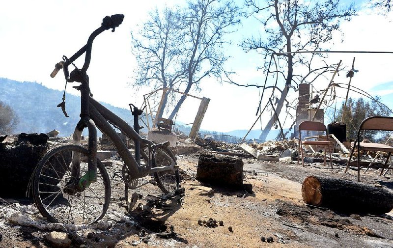 A child’s burned bicycle on Tuesday sits at a house destroyed by a wildfire outside Oakhurst, Calif.