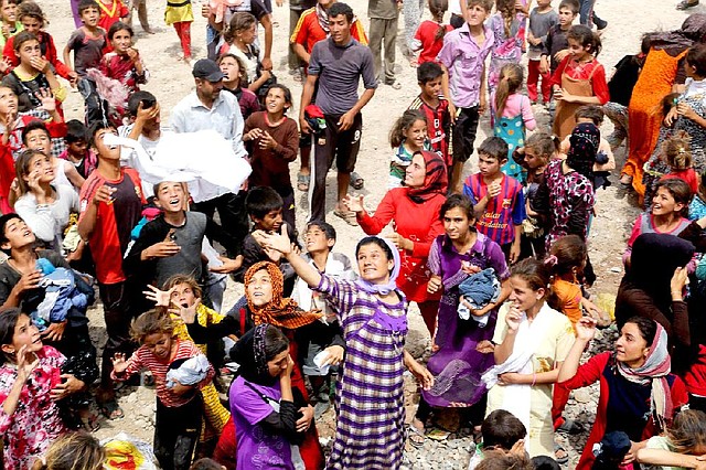 Iraqi refugees try to catch clothing provided by charity workers Tuesday at a new camp outside the Bajid Kandala camp at Feeshkhabour in northern Iraq.