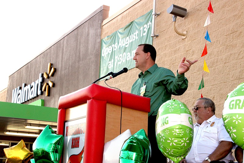 LYNN KUTTER ENTERPRISE-LEADER Jesse Pinkston, manager of the new Neighborhood Market in Farmington, welcomes a large crowd to the grand opening ceremony Aug. 13. Fire Chief Mark Cunningham is on the stage behind Pinkston. Others on the platform included police Chief Brian Hubbard, Mayor Ernie Penn and representatives of organizations that received grants from Walmart.