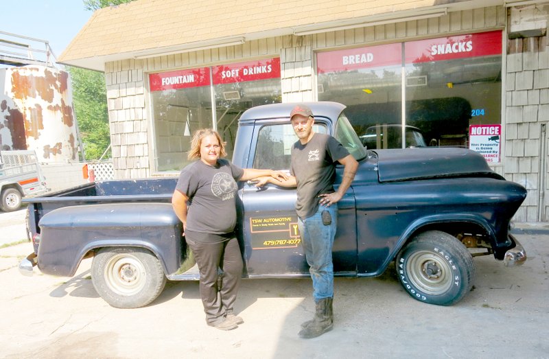 Photo by Susan Holland Shelly and Travis Walls, owners and operators of TSW Automotive, pose in front of an old vehicle they are fixing up for a friend. The Walls family has recently moved their business into the old Shop &#8216;n Go building in Gravette.