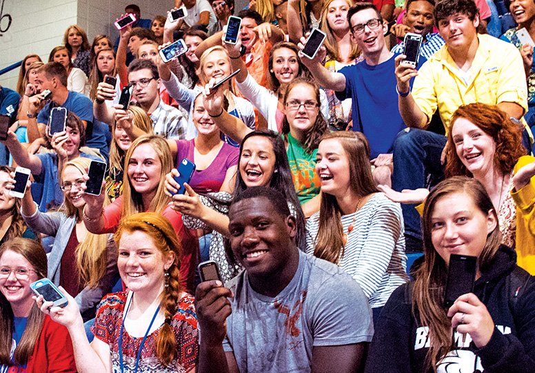 Seniors from Arkadelphia High School hold up their cellphones during an assembly. The administration embraces the idea of technology in the classroom and allows students to use the phones during class.