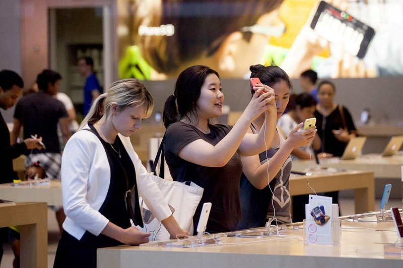 Shoppers look at iPhones last month at the Apple Inc. store on Manhattan’s Upper West Side in New York.