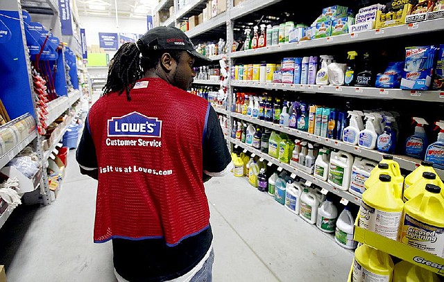 A Lowe’s employee walks down an aisle in the store in Saugus, Mass., in this file photo. The company said it plans to open 15 stores this year.