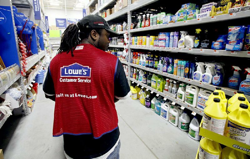 A Lowe’s employee walks down an aisle in the store in Saugus, Mass., in this file photo. The company said it plans to open 15 stores this year.