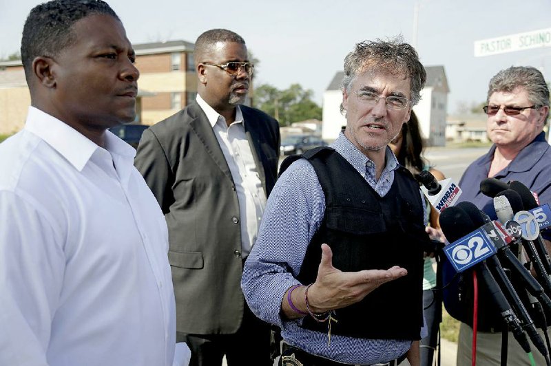 Harvey, Ill., Mayor Eric J. Kellogg (left) and city spokesman Sean Howard (second from left) stand by as Cook County Sheriff Tom Dart addresses the news media after about two dozen heavily armed law enforcement officers stormed a home in Chicago suburb Wednesday to free four remaining hostages and capture two suspects, ending a standoff that lasted more than 20 hours.