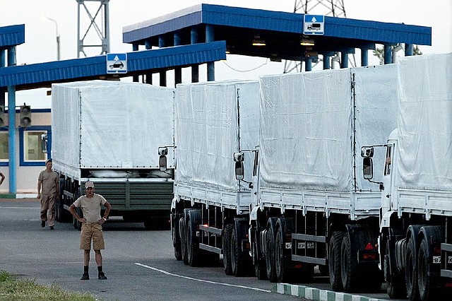 A driver stands near trucks as the first part of a Russian aid convoy is parked Wednesday inside a border control point with Ukraine.