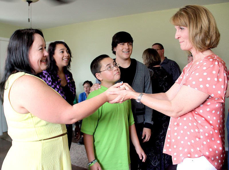 Staff Photo LYNN KUTTER Gaye Wilcox, president of Washington County Habitat for Humanity Board of Directors, hands over the key to the house to Rebecca Ponder and her children, Elena Juarez, Austen Juarez and Antonio Juarez. A dedication ceremony was held in late July at the new home in Prairie Grove.