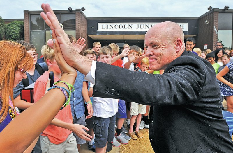 STAFF PHOTO BEN GOFF &#8226; @NWABenGoff Poore high-fives students after getting doused in ice water.
