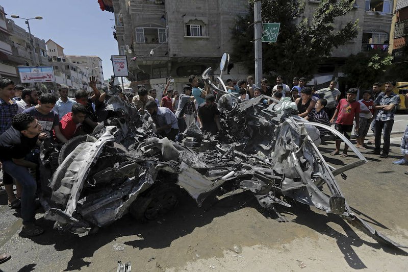 Palestinians move the wreckage of a vehicle following an Israeli airstrike off the main street in Gaza City in the northern Gaza Strip on Thursday, Aug. 21, 2014. At least two were killed in the car outside a grocery shop, and a few others were wounded by an Israel airstrike on a Gaza City street, according to the Palestine Red Crescent Society. 