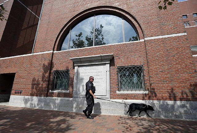 A police officer and his canine partner patrol outside federal court in Boston, Thursday, Aug. 21, 2014. A college friend of Boston Marathon bombing suspect Dzhokhar Tsarnaev pleaded guilty Thursday of impeding the investigation into the deadly attack. Dias Kadyrbayev, 20, is accused of removing a backpack containing emptied-out fireworks from Tsarnaev's dorm room after realizing he was suspected of carrying out the 2013 attack with his brother, Tamerlan Tsarnaev. (AP Photo/Elise Amendola)