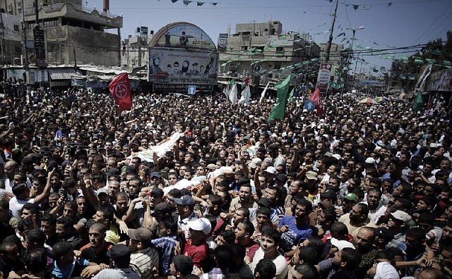 Palestinian mourners carry the body of three senior commanders of the Hamas military wing, Mohammed Abu Shamaleh, Raed Attar and Mohammed Barhoum, who were killed in early morning Israeli strikes, during their funeral in the Rafah refugee camp, Southern Gaza Strip, Thursday, Aug. 21, 2014. (AP Photo/Khalil Hamra)