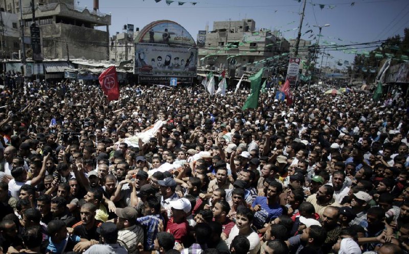 Palestinian mourners carry the body of three senior commanders of the Hamas military wing, Mohammed Abu Shamaleh, Raed Attar and Mohammed Barhoum, who were killed in early morning Israeli strikes, during their funeral in the Rafah refugee camp, Southern Gaza Strip, Thursday, Aug. 21, 2014. (AP Photo/Khalil Hamra)