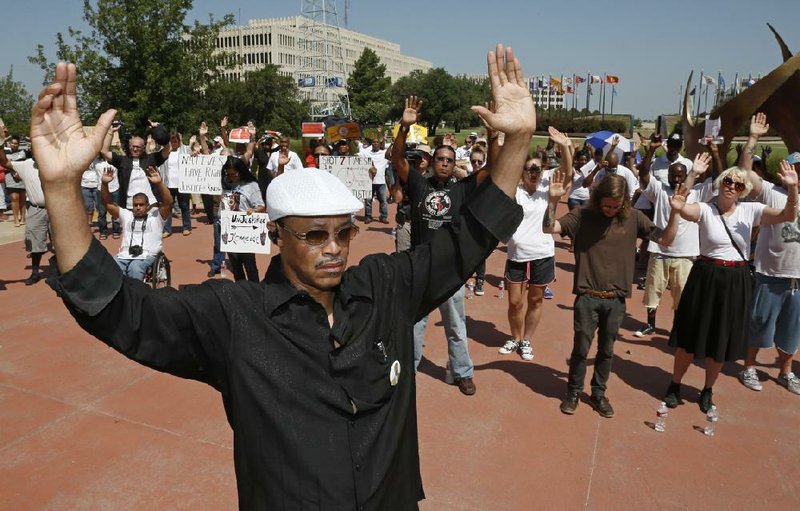 Participant Michael Washington holds his hands in the air during a rally in Oklahoma City, Thursday, Aug. 21, 2014, in response to the shooting death of 18-year-old Michael Brown in Ferguson, Mo. The Oklahoma City rally called "Hold Your Hands Up, Don't Shoot! Make Your VOTE Count Rally," featured speakers from groups including the National Association for the Advancement of Colored People, American Civil Liberties Union, Council on American-Islamic Relations and the gay rights organization - Cimarron Alliance. (AP Photo/Sue Ogrocki)