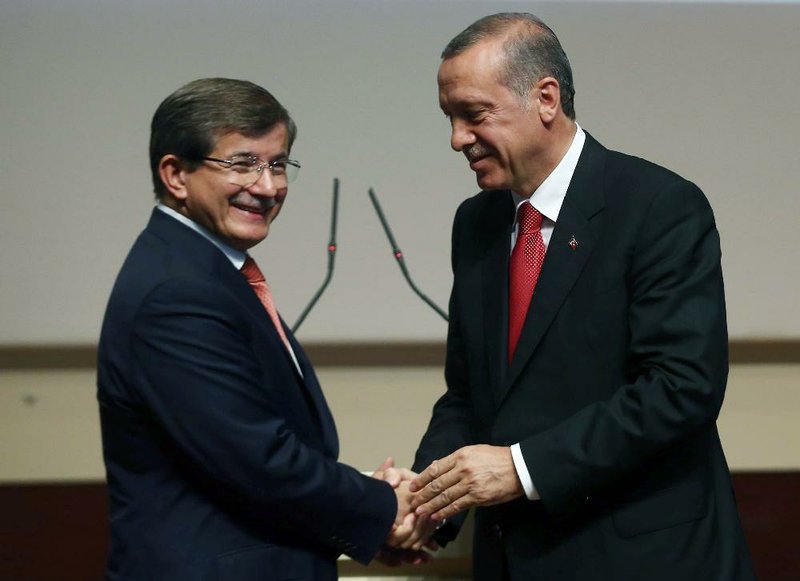 Turkey's president-elect Recep Tayyip Erdogan, right, greets Foreign Minister Ahmet Davutoglu after he announced Davutoglu as his ruling Justice and Development Party's new leader, in Ankara, Turkey, Thursday, Aug. 21, 2014.   Davutoglu, hand-picked by president-elect Erdogan to succeed him as prime minister, is expected to accept the largely backseat role although he is known to be an ambitious politician. (AP Photo/Burhan Ozbilici)