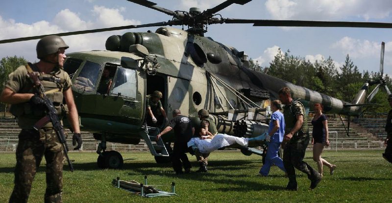 Ukrainian soldiers evacuate a wounded comrade close to Luhansk, eastern Ukraine, Thursday, Aug. 21, 2014.  The rebel stronghold 20 kilometers from the Russian border has been under siege for 19 days, lacking basic amenities like running water or electricity. (AP Photo/Petro Zadorozhnyy)