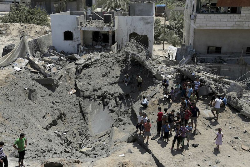 Palestinians look at a crater made after a house was hit by an Israeli airstrike in Gaza in the northern Gaza Strip on Friday, Aug. 22, 2014.