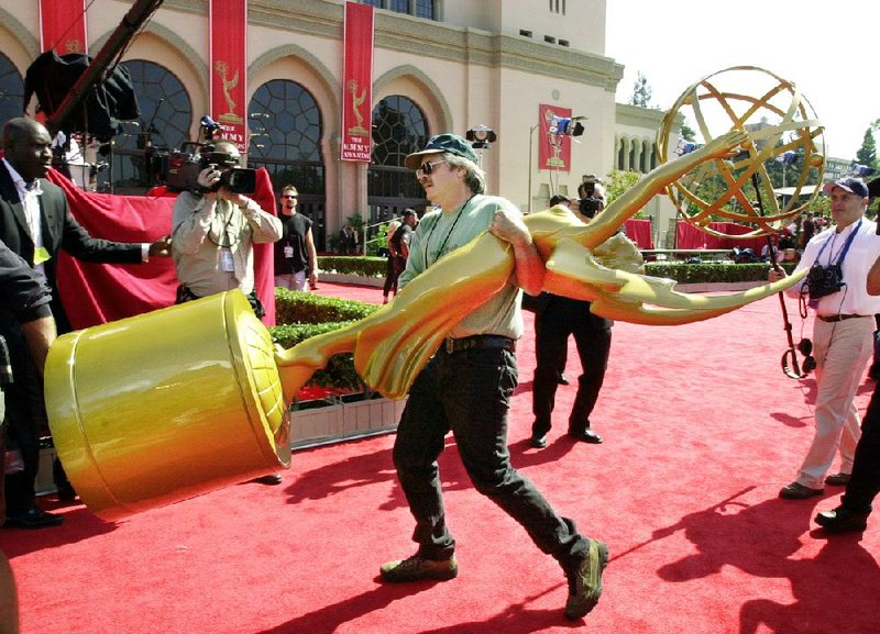 A worker removes an Emmy statue from the red carpet at the Shrine Auditorium in Los Angeles, Sunday, Oct. 7, 2001, following the cancellation of the 53rd annual Primetime Emmy Awards. The awards telecast, delayed three weeks by the Sept. 11 terrorist attacks, was canceled Sunday after the United States and Britain launched a military attack in Afghanistan. (AP Photo/Laura Rauch)