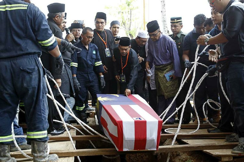 Mourners bury Nur Shazana, a crew member who was killed in July when a Malaysia Airlines flight was shot down over eastern Ukraine. The bodies and ashes of Malaysian victims of the downing were returned home Friday, where they received military honors and a day of national mourning was declared. 