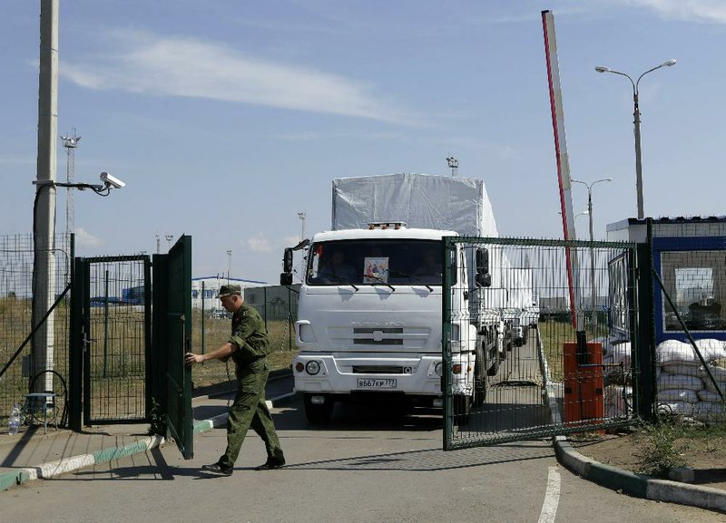 A Russian border guard opens a gate Friday for the first trucks of a Russian aid convoy heading into Ukraine after more than a week’s delay and without Kiev’s permission.