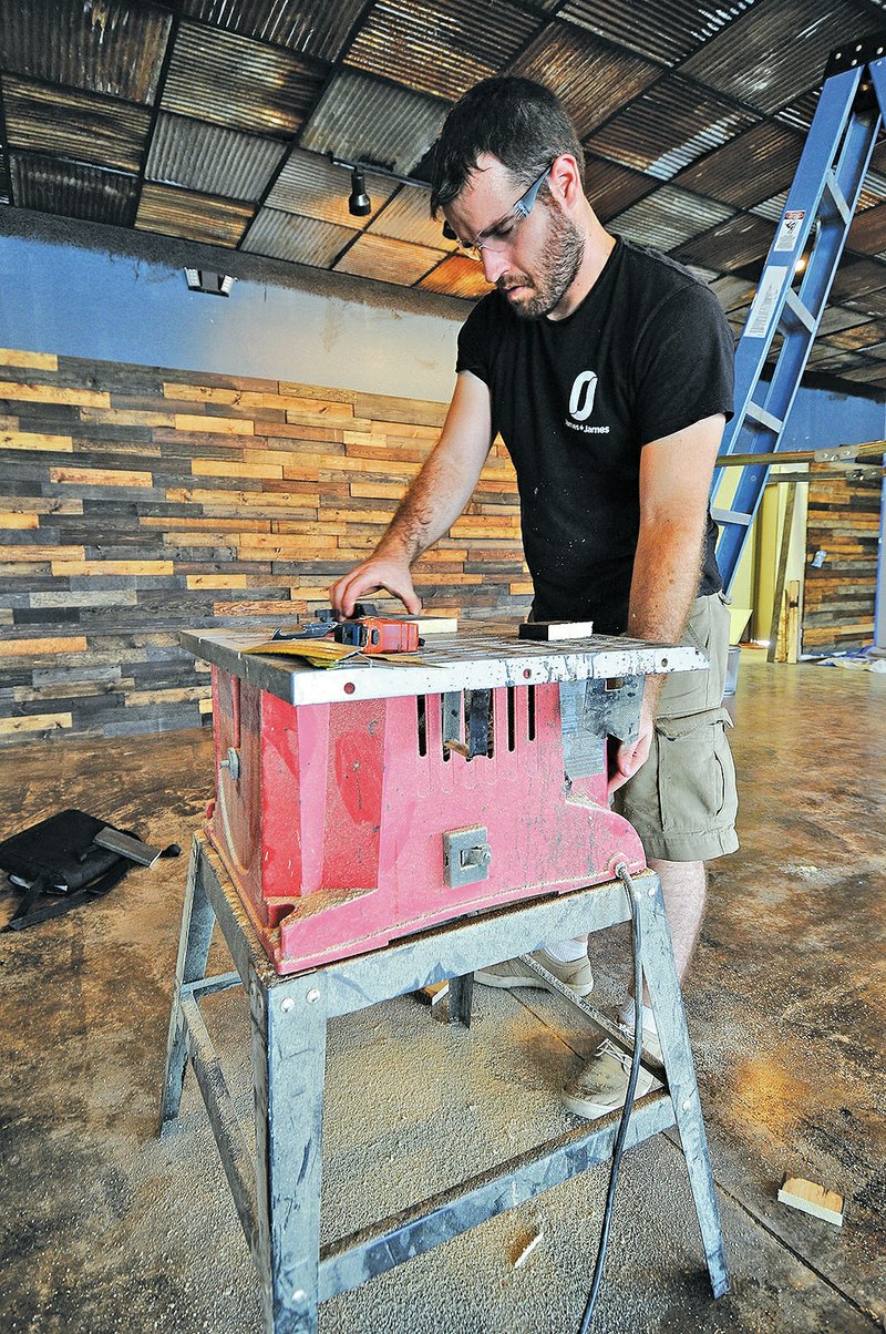 STAFF PHOTO J.T. Wampler James Smith of James+James cuts wood Wednesday while getting the company&#8217;s first retail store ready to open Monday.