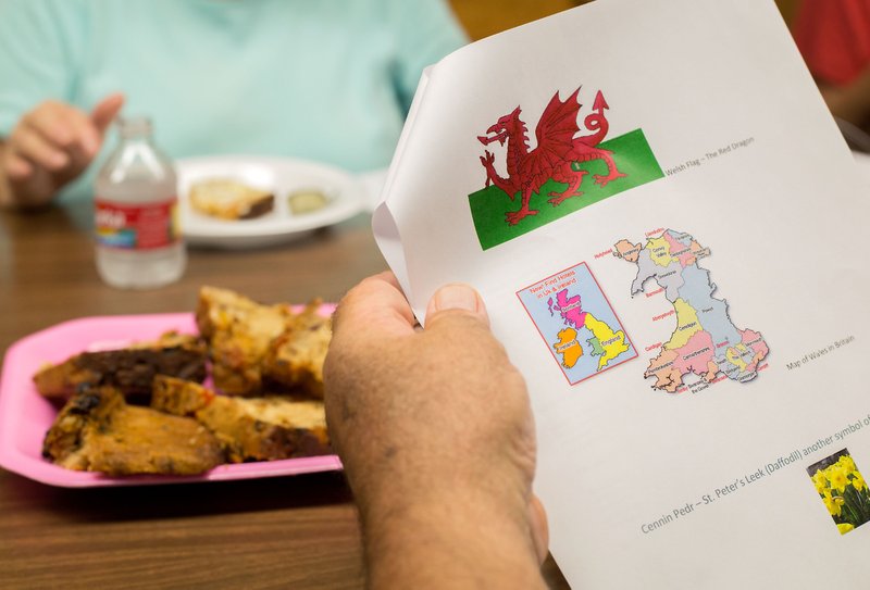 STAFF PHOTO JASON IVESTER The Rev. David Benham, rector of St. Andrew&#8217;s Episcopal Church in Rogers looks over information on Welsh culture during a Welsh class Tuesday at the church. The Welsh flag has sported a red dragon since Celtic times, explained teacher Kedron Benham, the pastor&#8217;s son. Welsh people wear daffodils to celebrate their patron saint on St. David&#8217;s Day on March 1.