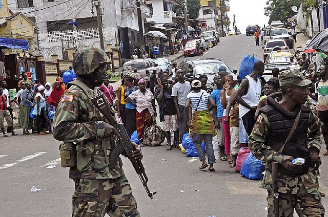 Liberian soldiers scan people for signs of the Ebola virus, as they control people from entering the West Point area in the city of  Monrovia, Liberia, Saturday, Aug. 23, 2014. The outbreak also continues to spread elsewhere in West Africa, with 142 more cases recorded, bringing the new total to 2,615 with 1,427 deaths, the World Health Organization said Friday. Most of the new cases are in Liberia, where the government was delivering donated rice to a slum where 50,000 people have been sealed off from the rest of the capital in an attempt to contain the outbreak. (AP Photo/Abbas Dulleh)