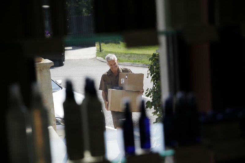 In this June 20, 2014 photo, United Parcel Service driver Marty Thompson is seen through the display window carrying boxes to deliver to Joseph and Friends Lifestyle Salon and Spa in Cumming, Ga. (AP Photo/David Goldman) 