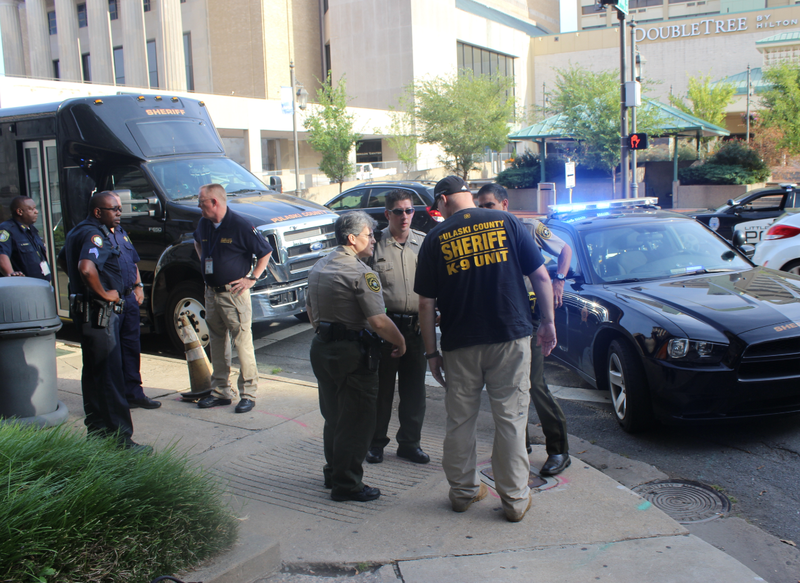 Authorities huddle on the sidewalk at Markham and Center Streets in downtown Little Rock Monday morning shortly after an inmate escaped while being taken into the Pulaski County Courthouse.