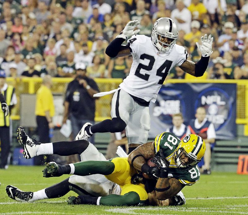 Green Bay Packers' Andrew Quarless catches a touchdown pass in front of Oakland Raiders' Charles Woodson (24)during the first half of an NFL preseason football game Friday, Aug. 22, 2014, in Green Bay, Wis. (AP Photo/Morry Gash)