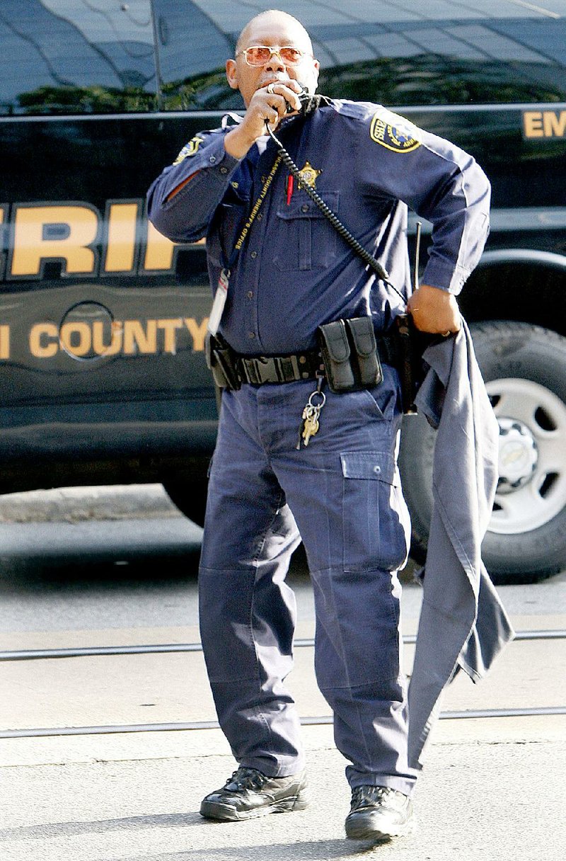 Arkansas Democrat Gazette/JEFF MITCHELL - 08/252014 - A Pulaski County Sheriff deputy talks on the radio after finding a piece of clothing from an escaped prisoner in downtown Little Rock, August 25, 2014. The county inmate escaped at the Pulaski County courthouse during a routine prisoner transfer.