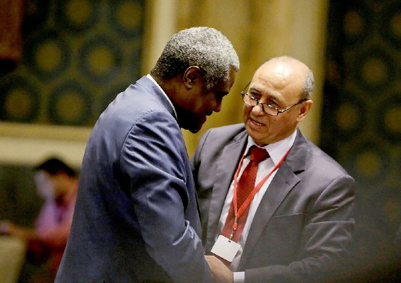 Libyan Foreign Minister Mohamed Abdelaziz, right, greets his Chadian counterpart Moussa Faki during the opening session of  a gathering of foreign ministers of Libya's neighbors in Cairo, Egypt, Monday, Aug. 25, 2014. Foreign ministers from Egypt Libya, Algeria, Tunisia, Sudan, and Chad, as well as the Arab League Secretary General, met Monday as weeks of inter-militia fighting has wreaked havoc in Libya. It's the worst violence in Libya since the 2011 downfall and killing of dictator Moammar Gadhafi. (AP Photo/Amr Nabil)