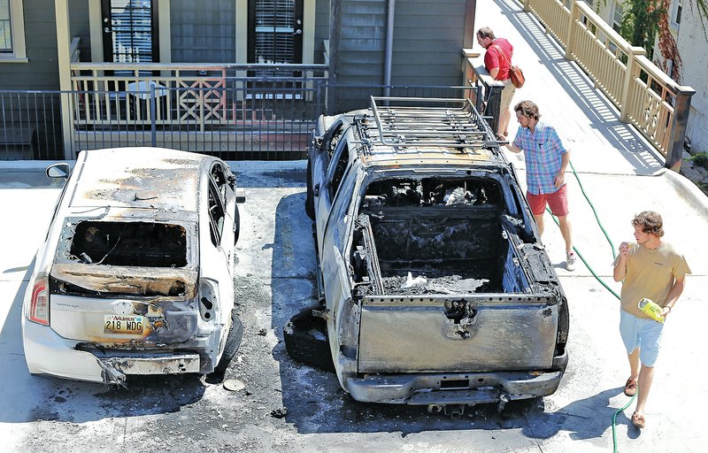 STAFF PHOTO DAVID GOTTSCHALK Two burned vehicles sit Monday in The Courts At Whitham apartment complex at 700 block of West Douglas Street in Fayetteville.