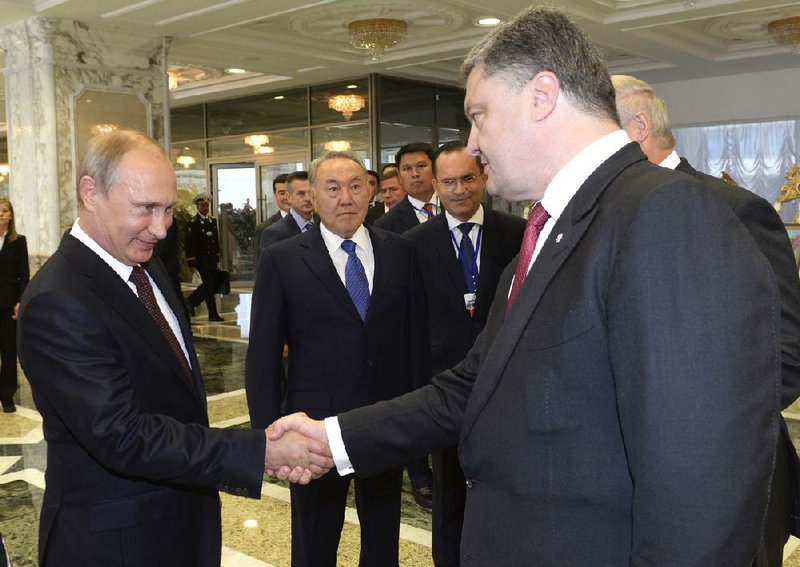 Russian President Vladimir Putin (left) and Ukrainian President Petro Poroshenko greet each other Tuesday before the start of their talks in Minsk, Belarus. Behind them is Kazakh President Nursultan Nazarbayev.