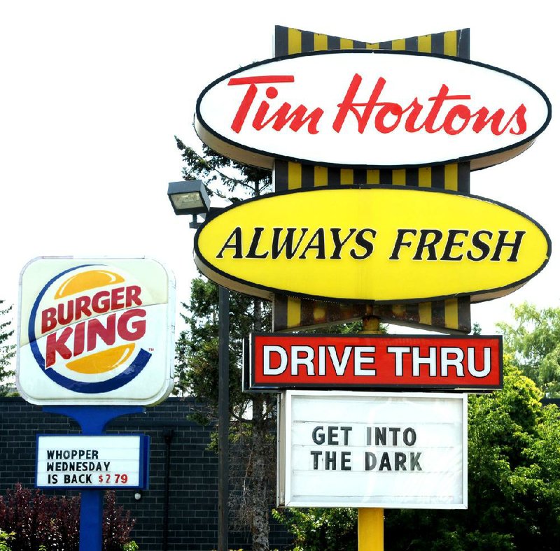 A Burger King sign and a Tim Hortons sign are displayed on St. Laurent Boulevard in Ottawa, Canada, on Monday, Aug. 25, 2014. Canada's iconic coffee chain, Tim Hortons, and Miami-based Burger King say they will join forces, but will operate as independent brands to form the world's third-largest quick service restaurant company. (AP Photo/The Canadian Press, Sean Kilpatrick)