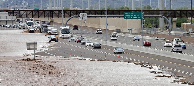 FILE - This Aug. 19, 2014 file photo shows flash flood waters from the overrun Skunk Creek flood I-10 in northwestern Phoenix. Global warming is here, human-caused and can already be considered dangerous, a draft of a new international science report says, warning that it is increasingly likely that climate change could be irreversible. The United Nations’ Intergovernmental Panel on Climate Change on Monday sent governments a final draft of its synthesis report, which combines three earlier, gigantic documents by the Nobel Prize-winning group. There is little in the report, that wasn’t in the other more-detailed versions, but the language is more stark and the report attempts to paint a bigger picture of the problem caused by the burning of fossil fuels, such as coal, oil and gas. (AP Photo/Matt York, File)