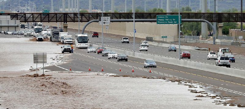 FILE - This Aug. 19, 2014 file photo shows flash flood waters from the overrun Skunk Creek flood I-10 in northwestern Phoenix. Global warming is here, human-caused and can already be considered dangerous, a draft of a new international science report says, warning that it is increasingly likely that climate change could be irreversible. The United Nations’ Intergovernmental Panel on Climate Change on Monday sent governments a final draft of its synthesis report, which combines three earlier, gigantic documents by the Nobel Prize-winning group. There is little in the report, that wasn’t in the other more-detailed versions, but the language is more stark and the report attempts to paint a bigger picture of the problem caused by the burning of fossil fuels, such as coal, oil and gas. (AP Photo/Matt York, File)