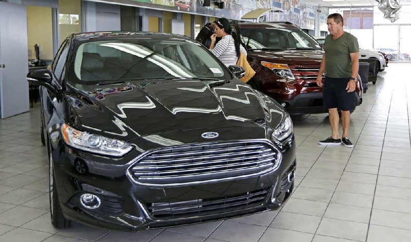 In this photo taken Aug. 21, 2014, Orestes Perez, right, and his niece Yanuska Perez, check a 2013 Ford Fusion SE at a local dealership in Hialeah, Fla. The Commerce Department reports on business orders for durable goods in July on Tuesday, Aug. 26, 2014. (AP Photo/Alan Diaz)