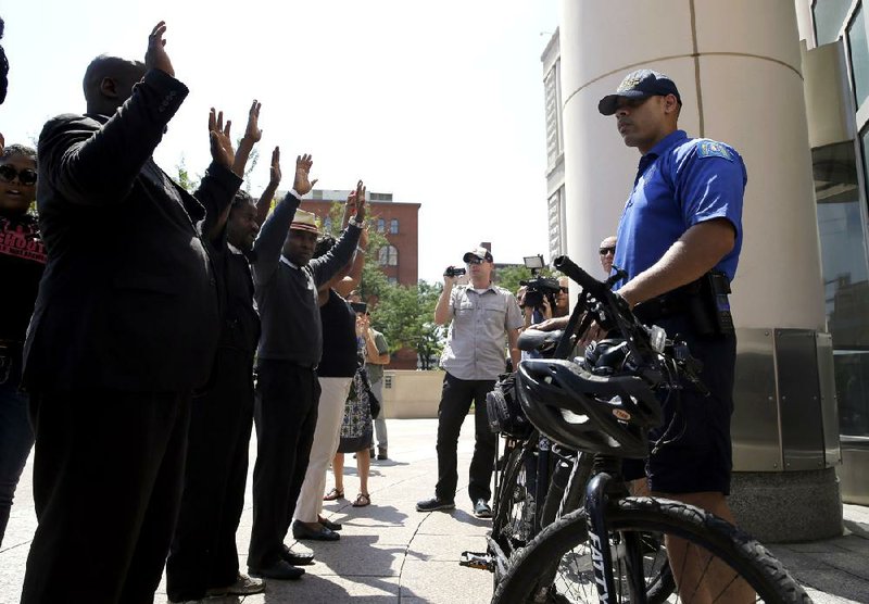 A member of the St. Louis Police Department blocks the doors of Thomas F. Eagleton federal courthouse as protesters demonstrate outside, Tuesday, Aug. 26, 2014, in St. Louis. About 100 protesters marched as they continue to press for broader reforms to local and federal law enforcement following the shooting death of Michael Brown by police. (AP Photo/Jeff Roberson)