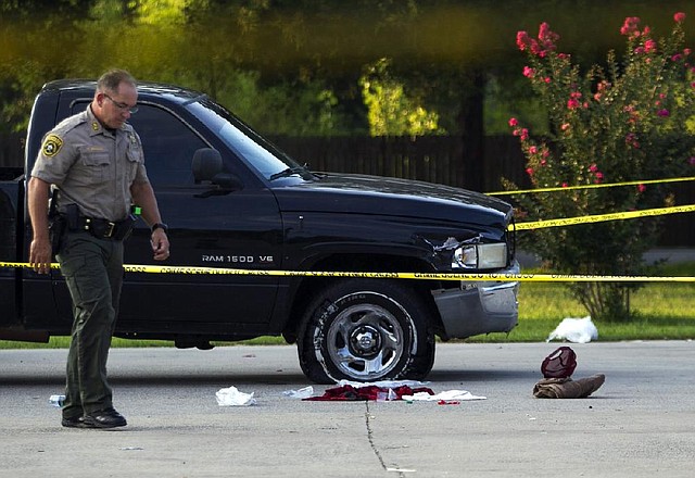 A Pulaski County sheriff’s deputy examines the clothing left in a parking lot at Dollar General store on Arkansas 365 in Marche by a victim after a shooting was reported at former professional boxing champion Jermain Taylor’s house nearby. The extent of the victims injuries was unclear.
