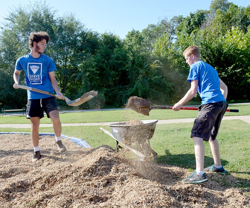 Janelle Jessen/Herald-Leader David Munez of Siloam Springs and Harrison Briscoe of Wichita, Kan., scooped wood chips into a wheelbarrow to spread on the playground in Bob Henry Park.