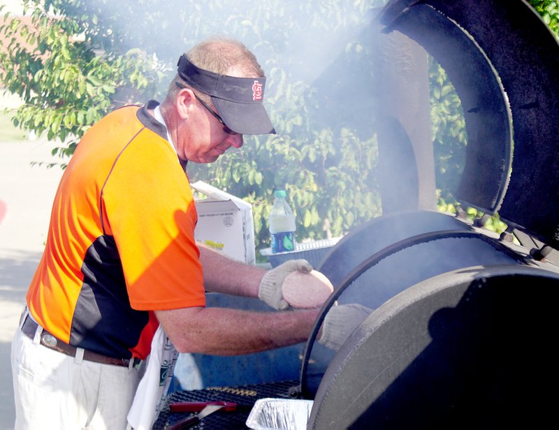 Photo by Randy Moll Jeff Hendren, of the Gravette Athletic Booster Club, begins to grill hamburgers for the school district&#8217;s Fall Pride Night on Friday. The evening began with a meal and included an introduction of volleyball teams, football teams, golf teams, cheer squads and the school bands.