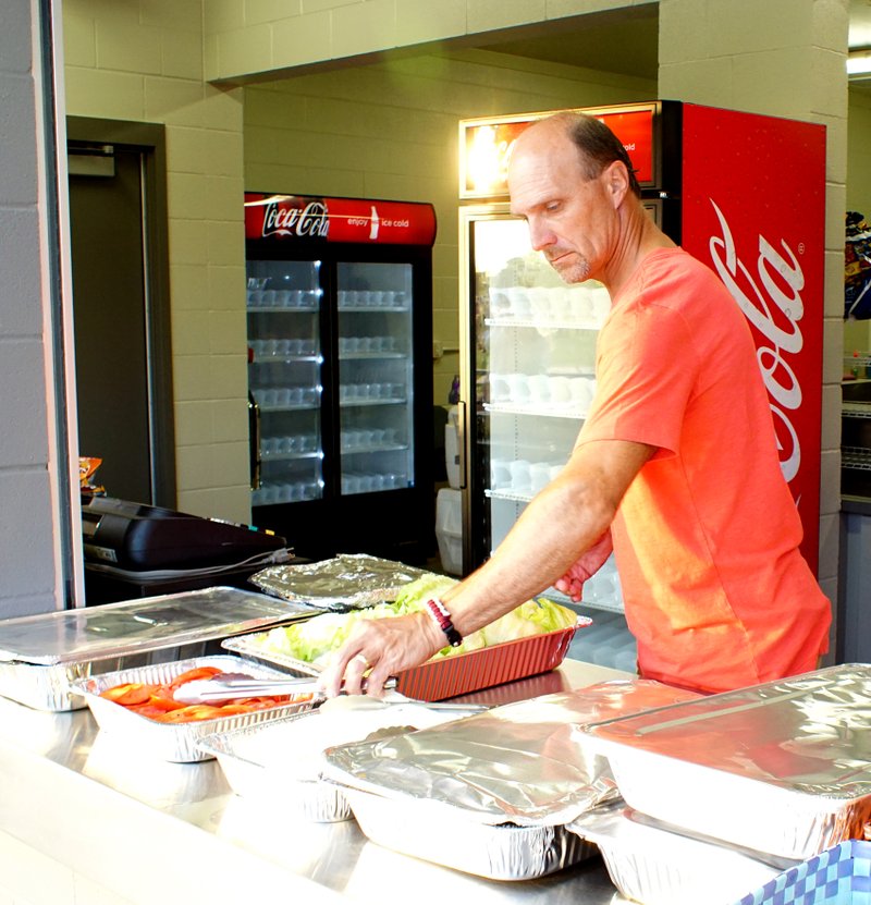 Photo by Randy Moll Eldon Cripps helps set up for the meal provided by Farm Bureau and the Gentry Athletic Booster Club during Meet the Pioneers Night at Pioneers&#8217; Stadium in Gentry on Friday. Band members, cheerleaders and members of athletic teams for Gentry&#8217;s fall sports were introduced to fans at the event.