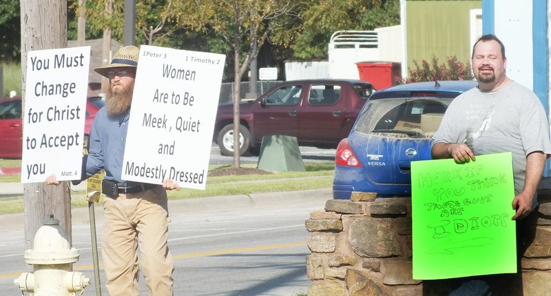 TIMES photograph by Annette Beard Shaun Landrus, right, and Wilbur Graybill held signs for passers by to see Monday evening at the four-way stop intersection of Slack Street/Curtis Avenue/Lee Town Road (Arkansas Highways 94/72).