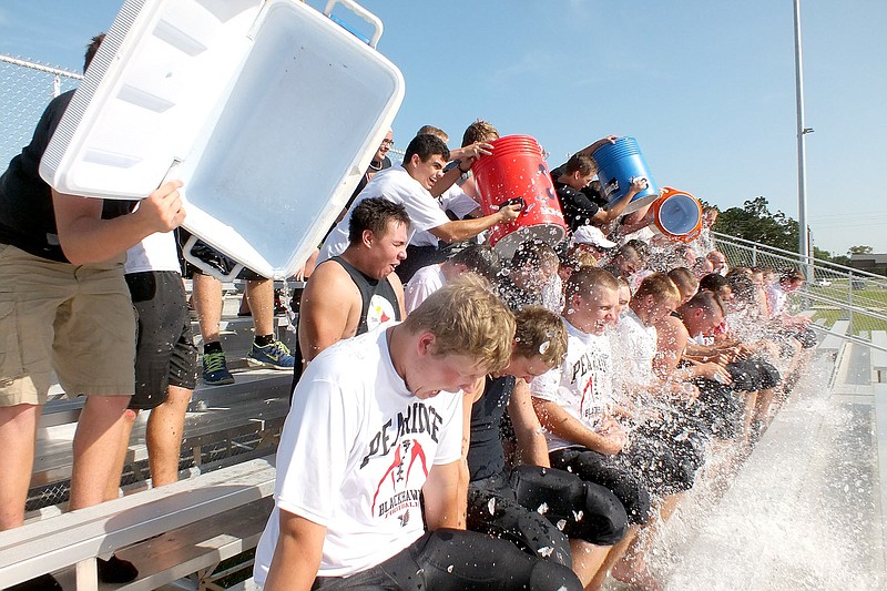 TIMES photograph by Annette Beard Sophomore and junior Blackhawks delighted in dousing senior Blackhawks and coaches with buckets of ice water answering a challenge by Gravette football coach and team. All of the football players were then hosed with water by Pea Ridge firefighters.